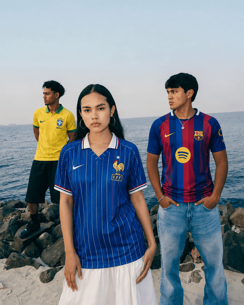 Three friends on the shoreline wearing France, Brazil, and Barcelona football jerseys